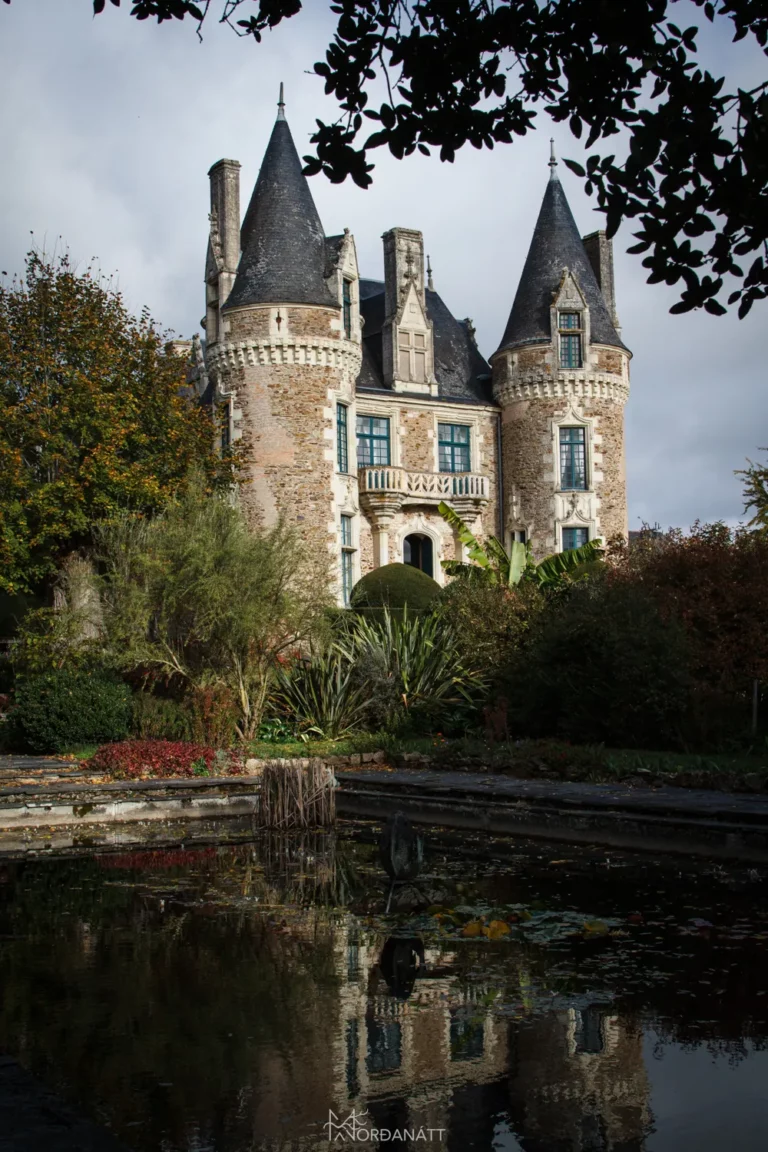 Photographie du Château du Pin en arrière plan, d'un plan d'eau et de verdure au premier plan